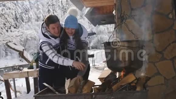 快乐的一对夫妇在冬天在木屋附近准备食物视频的预览图