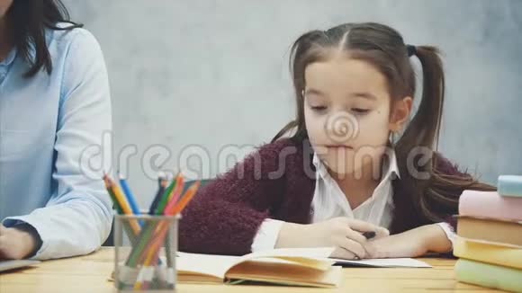 在灰色的背景下关闭母女在这期间一位年轻的母亲在笔记本电脑上工作视频的预览图