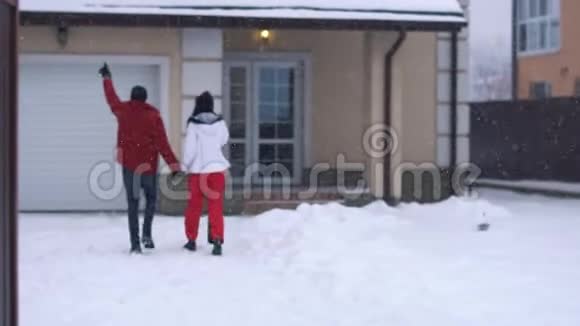 年轻的女人和留胡子的男人走在后院走向房子牵着手快乐的一对在冬天玩得开心视频的预览图