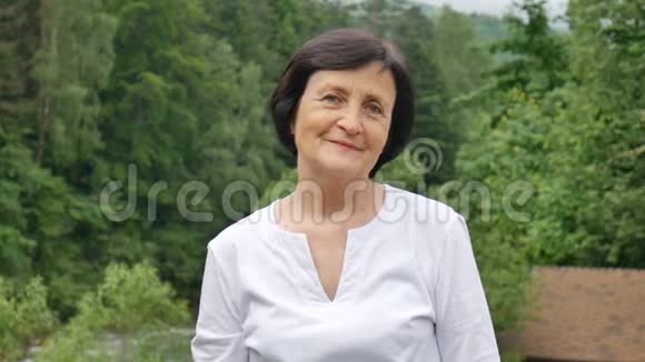 特写一位年长妇女的肖像她留着一头乌黑的短发满脸皱纹微笑着看着山上的摄像机视频的预览图