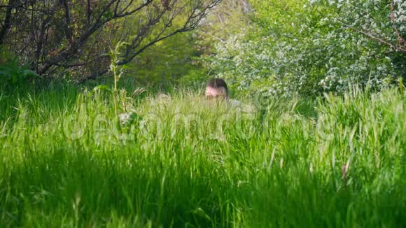 前景中有绿色多汁的草地背景中有一个戴着眼镜的人从草地上出去视频的预览图