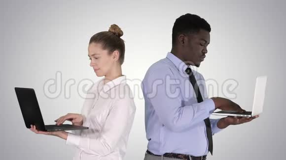 两个背靠背站着在渐变背景下工作在笔记本电脑上视频的预览图