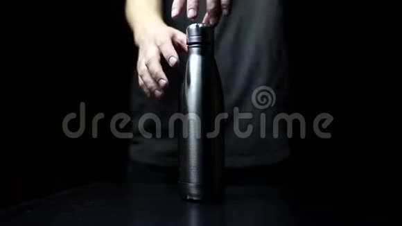 工作室形象特写男性手打开一个可重复使用的钢热水瓶在黑色背景视频的预览图