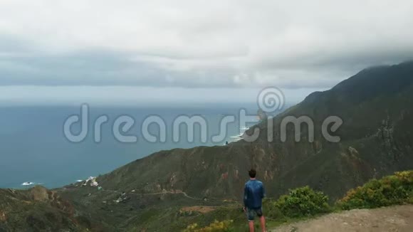 空中观景一个人站在山的边缘看着一幅美丽的风景大西洋的长海岸视频的预览图