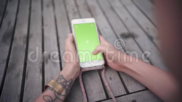一位年轻女士的特写手她用绿色屏幕色键垂直地握住和使用电话视频的预览图