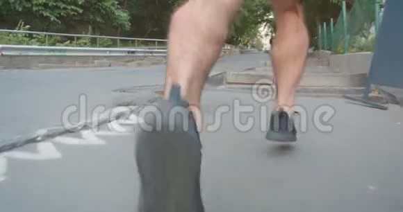 在城市户外的街道上慢跑的成年坚定运动的男跑步者的特写镜头视频的预览图