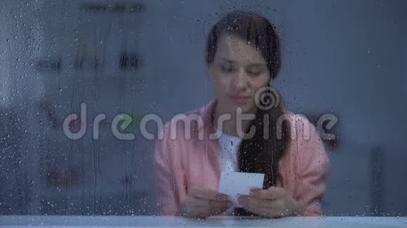 女人看着雨窗后的照片想起初恋视频的预览图