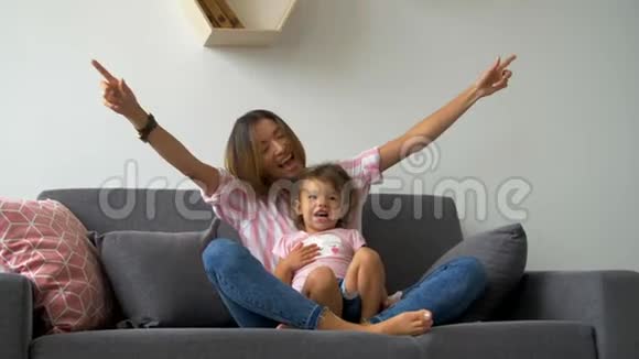 幸福美丽的爱的家庭年轻的母亲和女儿坐在沙发上笑微笑的母亲和孩子玩得开心享受骗局视频的预览图