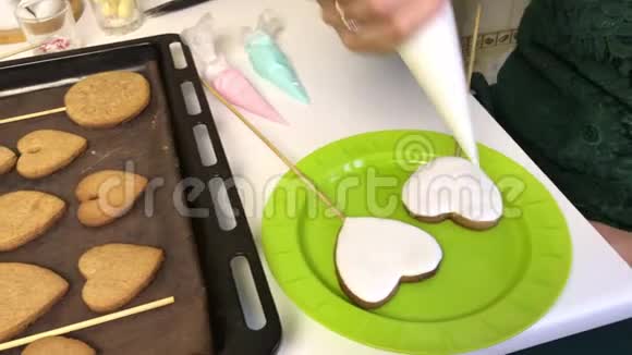 女人在姜饼上涂上糖霜饼干被放置在烤片旁边以便进一步上光视频的预览图