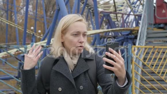 一位女博主在一个废弃的游乐园里智能手机在视频聊天视频的预览图