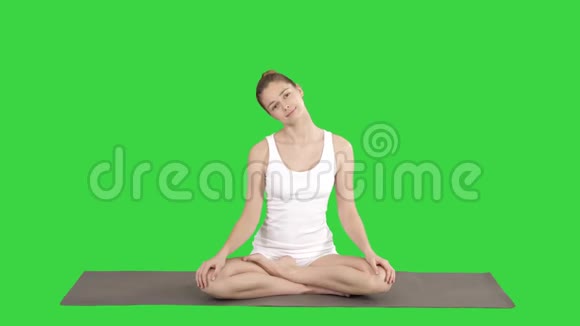 平静的女人练习瑜伽坐在莲花的姿势伸展脖子在绿色屏幕上Chroma键视频的预览图