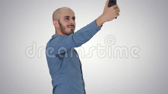 自拍时间英俊的年轻人在梯度背景上用手机自拍视频的预览图