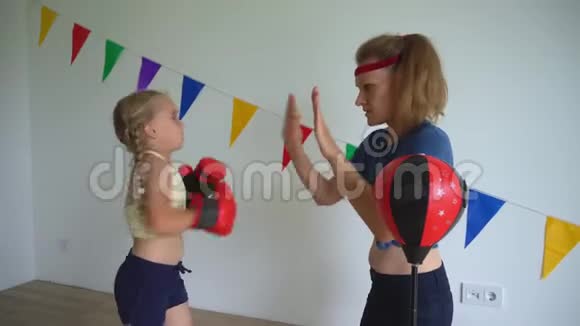 活跃的小女孩与她慈爱的母亲训练拳击幸福的家庭女孩视频的预览图