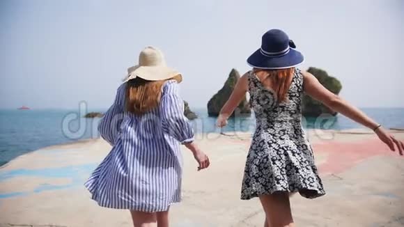阳光明媚的一天两个年轻的女人沿着长廊直奔大海视频的预览图