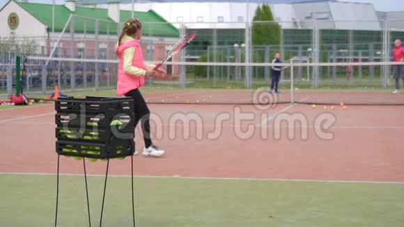 孩子们夏天在网球场上打网球与教练一起做运动打网球背景慢动作视频的预览图