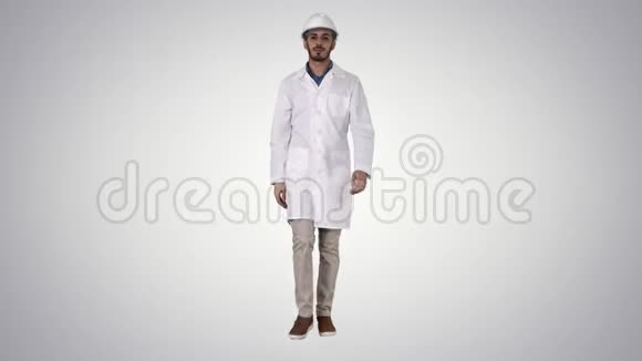戴着头盔和白色长袍的阿拉伯工程师在梯度背景下向前走视频的预览图