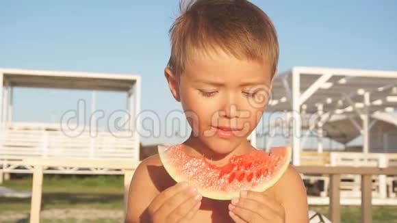 男孩在海滩边阳光明媚的背景下吃西瓜视频的预览图