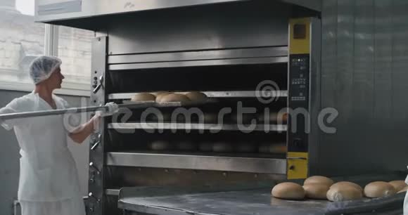 面包业的工人从烤箱里卸下煮熟的面包然后把面包装在特制的架子上视频的预览图