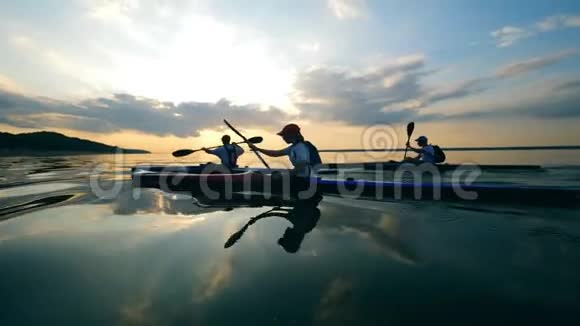一群划手正划过夕阳的水面视频的预览图