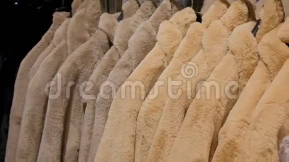 在一家零售时装店的衣架上出售的豪华人造毛皮冬季夹克快关门视频的预览图