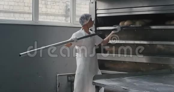 专业的面包店工作人员把烤好的面包从烤箱里卸下来然后装上货架他们工作得很快而且都是视频的预览图