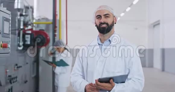 微笑着一个有魅力的大个子工程师他在一个大食品行业的协助下检查机器一个留着胡子的人视频的预览图