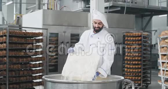 有魅力的面包师厨师把面粉装在一个大面包店里他微笑着心情很好视频的预览图