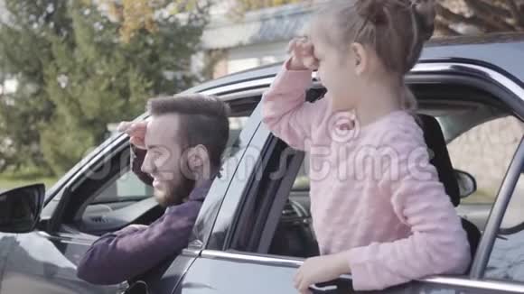 汽车后座上的肖像小女孩向窗外靠近父亲坐在司机视频的预览图