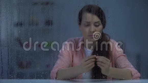 失望的女性在雨窗后抱着订婚戒指离婚观念视频的预览图