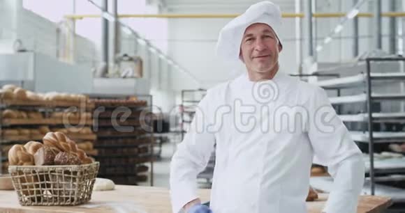 在一个大的面包店里一个漂亮的成熟男人面包师笑得很大在镜头前表现出很大的样子视频的预览图