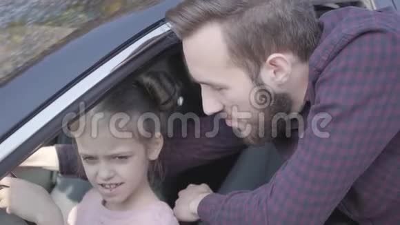 坐在驾驶座上的小女孩车座上抱着轮子紧紧地抱着这孩子正在学习开车视频的预览图