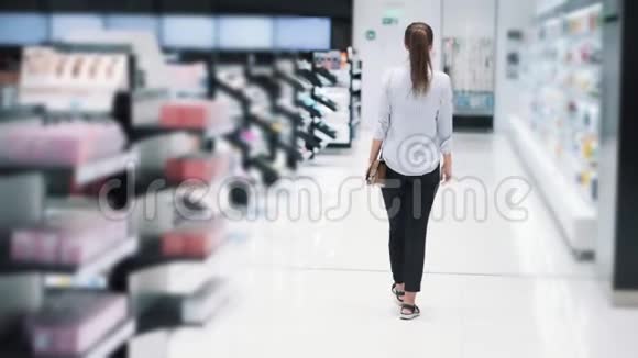 背面女孩在化妆品店购物在货架之间慢动作视频的预览图