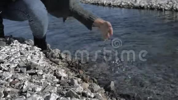 年轻的女孩滋润她的手蘸着清澈的水在岩石海岸阳光明媚的一天视频的预览图