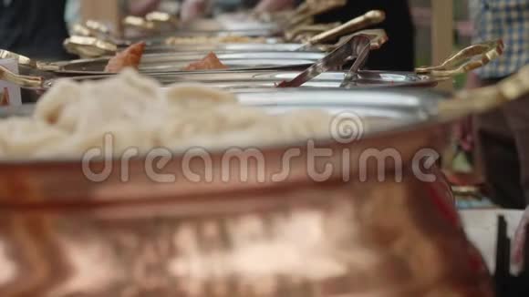 一排锡锅配有皮梅尼大米和其他亚洲食品背景是重点厨师的手在做食物视频的预览图