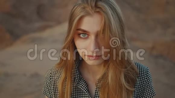 日落时漂亮金发女人的肖像幸福的年轻女子站在沙漠中夕阳西下慢悠悠视频的预览图