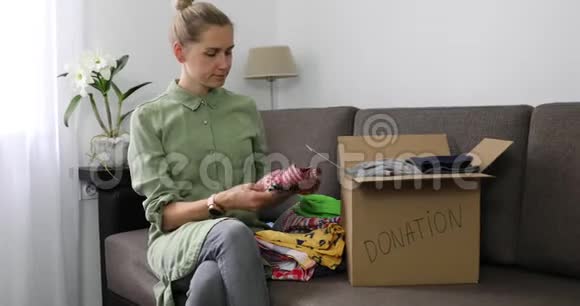 慈善妇女把儿童衣服放进纸板箱捐赠视频的预览图