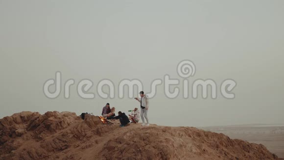 一群人在日落时分在山顶上放松坐在篝火旁享受他们的时光友谊青春视频的预览图