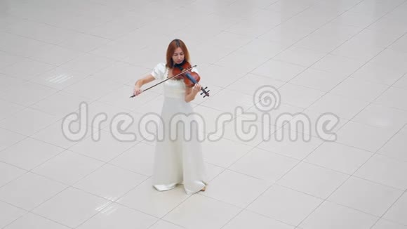 穿白色连衣裙的女人站在白色瓷砖上拉小提琴视频的预览图