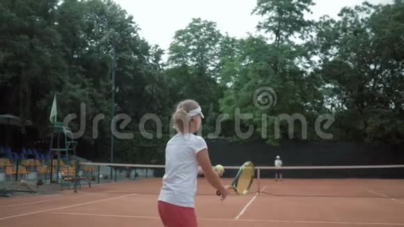 网球比赛两个运动的孩子在露天的红场上打网球和互相抛球视频的预览图