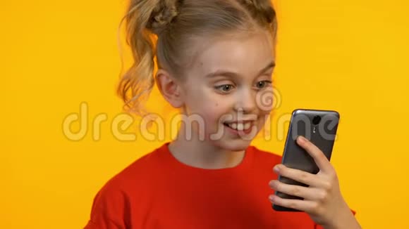 有趣的女孩子看手机和显示拇指向上教育应用程序视频的预览图