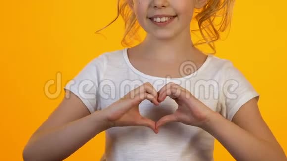小女孩用手显示心脏标志相机微笑爱的概念视频的预览图