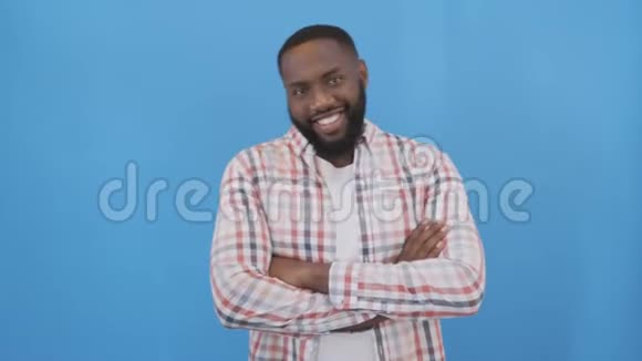穿格子衬衫的美国黑人帅哥蓝色背景上快乐的微笑男人4K视频的预览图