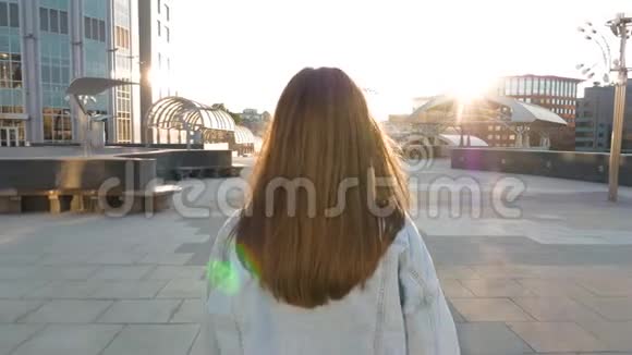 在日落时分一个棕色头发的女人沿着一条空荡荡的街道朝太阳走去视频的预览图