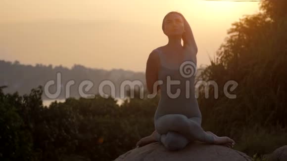 瑜伽练习者坐在gomukhasana的岩石慢速运动上视频的预览图