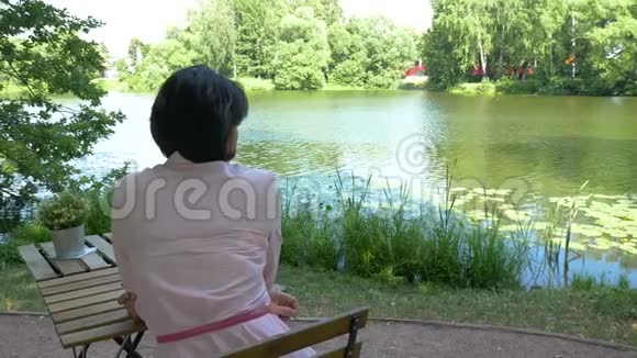 中年妇女在池塘边休息坐在一张桌子旁视频的预览图