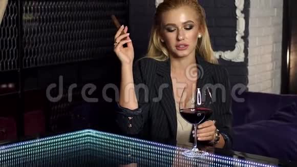 酒吧里有一支雪茄和一杯红酒的年轻美女画像视频的预览图