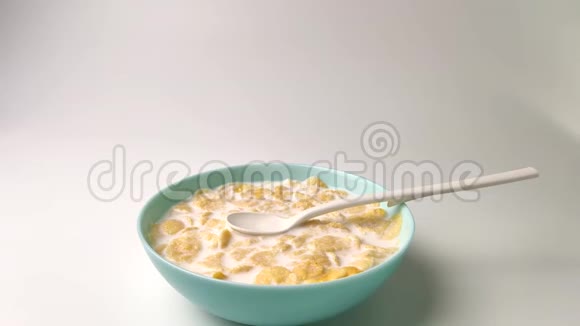 牛奶搅拌玉米片健康早餐白色背景下的慢镜头拍摄视频的预览图