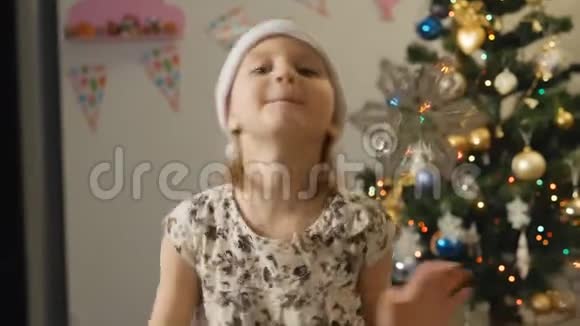 戴着圣诞帽的小女孩晚上坐在窗边的房间里视频的预览图