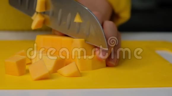 女厨师把南瓜切成小块南瓜在木板上煮南瓜奶油汤的原料视频的预览图