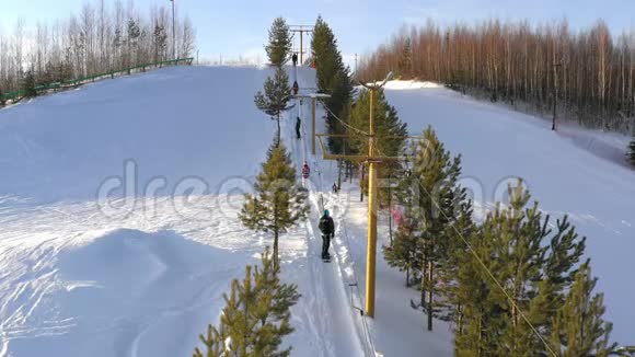 滑雪板在明亮的冬日升起滑雪者和滑雪者使用滑雪电梯爬山视频的预览图